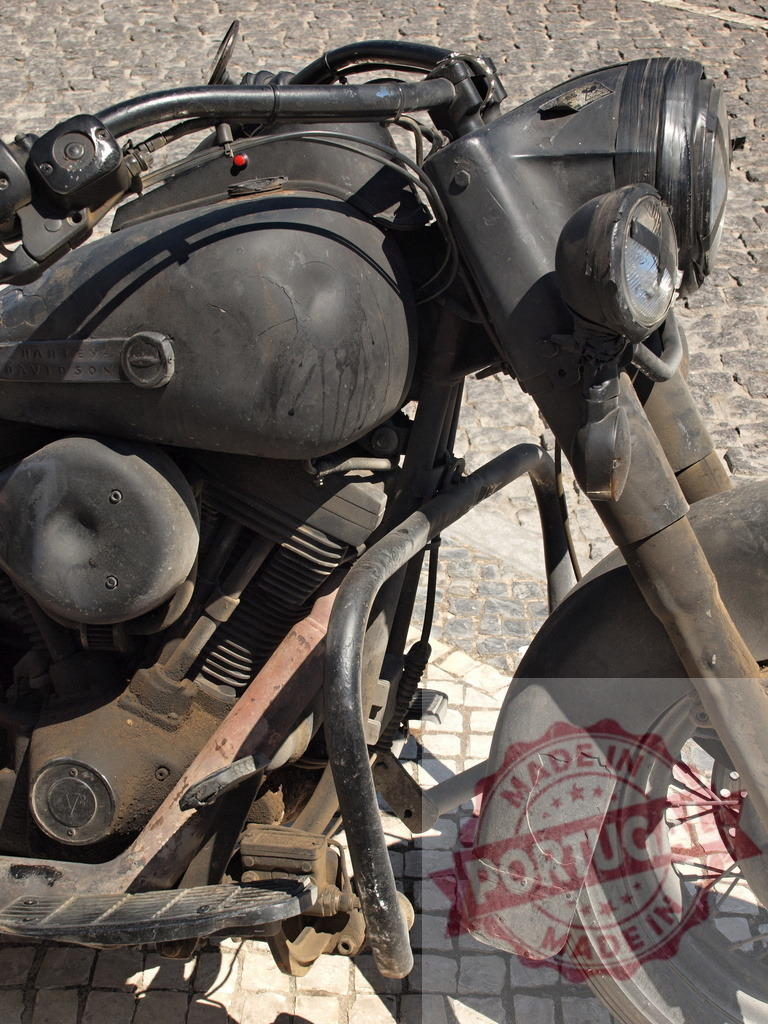 Harley-Davidson vintage motorcycle standing on cobblestone street | Harley-Davidson vintage dark motorcycle with custom matte finish and rusty details - Realisiert mit Pictrs.com