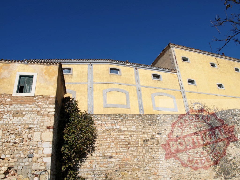 São Jorge castle yellow building with ancient stone wall | São Jorge Castle building showcasing traditional architecture and old stone wall below a blue sky - Realisiert mit Pictrs.com