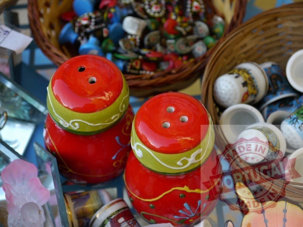 Colorful ceramic salt and pepper shakers in market | Hand-painted ceramic salt and pepper shakers displayed in an outdoor market stall - Realized with Pictrs.com