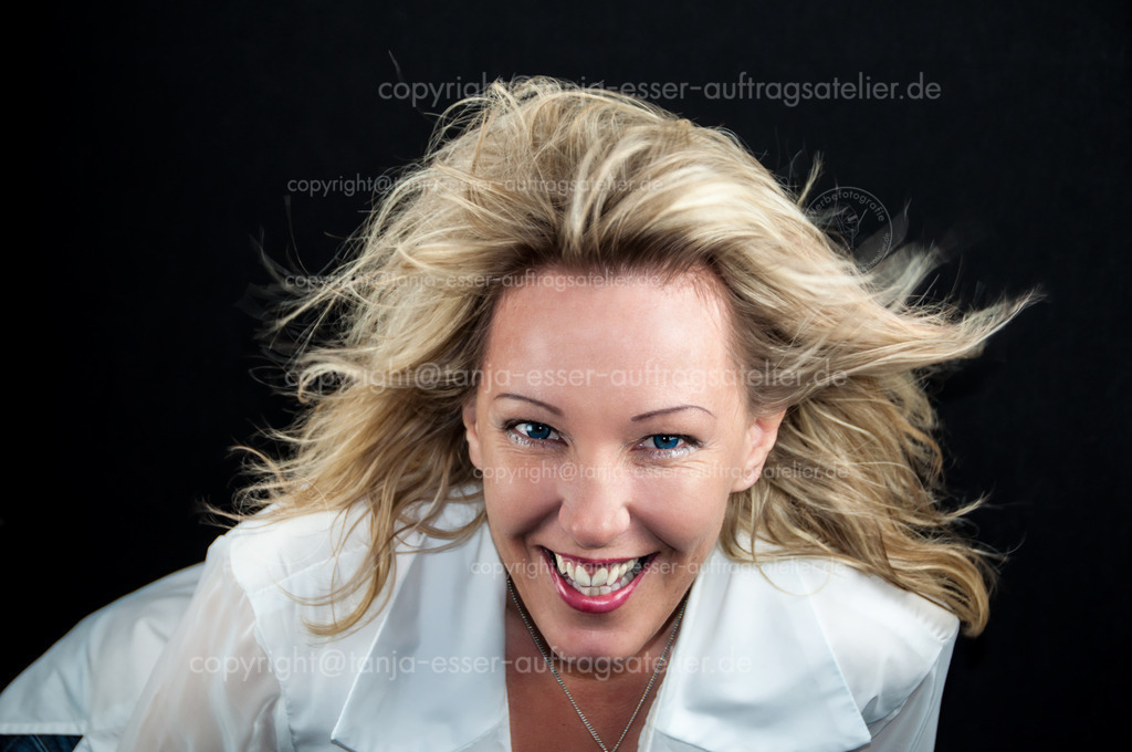 Frau im Wind D | Eine junge blonde Frau steht voller Energie im Wind. Die blonden langen Haare fliegen ihr aus dem Gesicht. Sie hat blaue Augen und eine Menge Kraft.