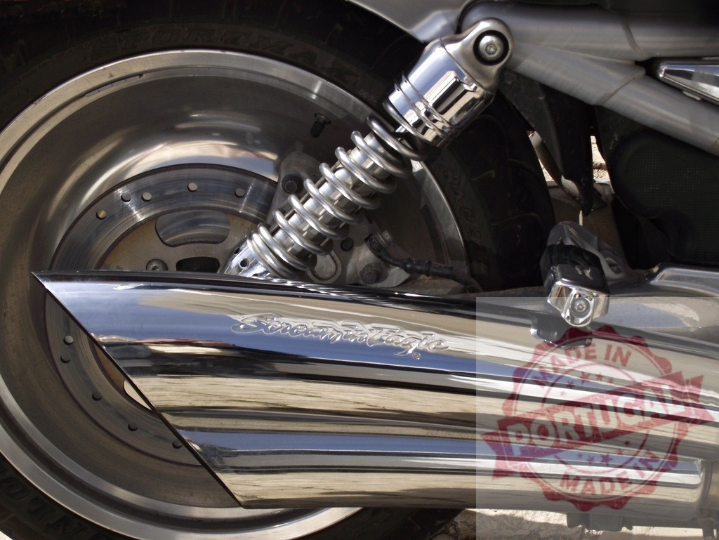 Motorcycle chrome exhaust pipe and rear wheel | Motorcycle chrome exhaust pipe showing shock absorber, brake disk, and tire detail - Realisiert mit Pictrs.com