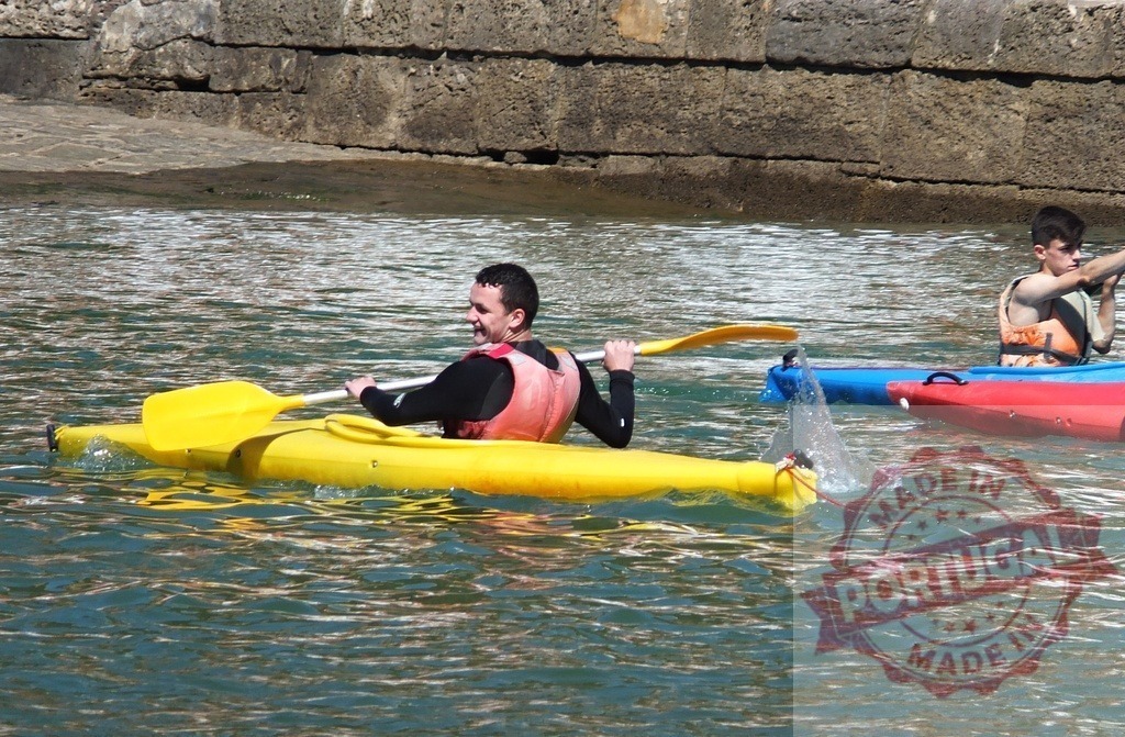 Man kayaking in yellow kayak on water | Man paddling a yellow kayak in calm water with another person nearby - Realisiert mit Pictrs.com