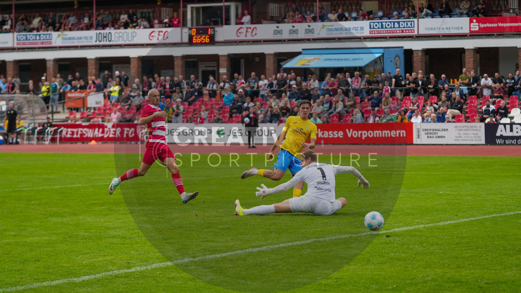 Fußball, Herren, Saison 2025/2026, Regionalliga Nordost, 9. Spieltag, Greifswalder FC vs. FSV 63 Luckenwalde, Sonntag 21.09.2025, Volksstadion Greifswald, | Fußball, Herren, Saison 2025/2026, Regionalliga Nordost, 9. Spieltag, Greifswalder FC vs. FSV 63 Luckenwalde, Sonntag 21.09.2025, Volksstadion Greifswald, Im Bild: Mike Bachmann (gelb, Luckenwalde) schiebt den Ball an Jakub Jakubov (weiß, Greifswald) vorbei. Im Hintergrund Steffen Eder (rot, Greifswald) - Realisiert mit Pictrs.com
