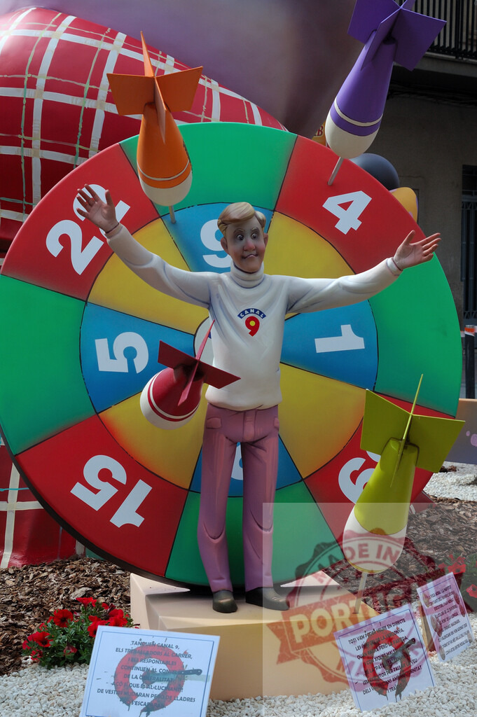 Fallas satire of Canal 9 character on a target wheel. Fallas Fiestas Communidad Valenciana | Satirical Fallas ninot representing a television personality on a target wheel hit by darts - Realisiert mit Pictrs.com