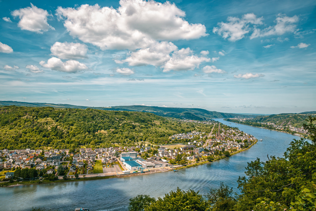 Panoramablick auf die berühmte Rheinschleife bei Boppard,Mittelrheintal | Dieses Foto zeigt einen Blick auf die berühmte Rheinschleife bei Boppard im UNESCO-Welterbe Oberes Mittelrheintal.Die Aufnahme wurde von einem der höher gelegenen Aussichtspunkte an den Hängen aufgenommen – sehr wahrscheinlich nahe dem bekannten Mittelrhein-Klettersteig oder dem Aussichtspunkt Vierseenblick / Gedeonseck.Sichtbare Orte: Im linken und mittleren Vordergrund am Flussufer ist der Bopparder Ortsbezirk Bad Salzig sowie Teile von Weiler zu sehen - Realisiert mit Pictrs.com