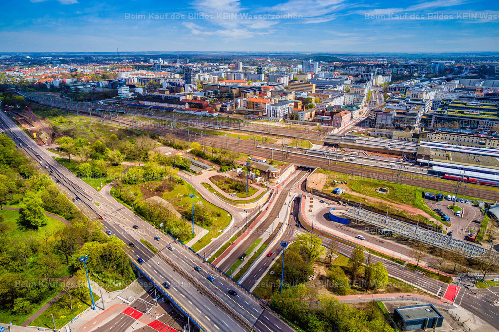 Magdeburg Damaschkeplatz neuer Tunnel Busbahnhof-0022 | Blick aus der Drohnenperspektive auf den Damaschkeplatz in Magdeburg. Im Vordergrund kreuzen sich mehrere Straßen und Verkehrsachsen, während dahinter die weitläufigen Gleisanlagen des Magdeburger Hauptbahnhofs verlaufen. Der Bereich verbindet den Straßenverkehr mit dem Bahnverkehr und bildet einen wichtigen Verkehrsknotenpunkt am westlichen Rand der Innenstadt. –  – Besonders auffällig sind die Brücken, Zu- und Abfahrten sowie die neu angelegte Verkehrsführung im Bereich des Damaschkeplatzes. Der Straßentunnel unter der Ernst-Reuter-Allee gehört zu den umfangreichen Verkehrsprojekten der Magdeburger Innenstadt. Er soll den Straßenverkehr unter den Bahnanlagen hindurchführen und die Verkehrsabläufe im Zentrum neu ordnen. –  – Das Luftbild zeigt den Bereich in einer Phase des Umbruchs: Neue Verkehrswege treffen auf bestehende Bahntrassen und die angrenzenden Grünflächen. Aus der Vogelperspektive werden die verschiedenen Ebenen der Infrastruktur besonders deutlich. Straßen, Brücken, Gleise und Wege bilden ein komplexes Netz, das sich vom Boden aus nur schwer in seiner Gesamtheit erfassen lässt. –  – Die Aufnahme vermittelt einen sachlichen Überblick über einen wichtigen Verkehrsknotenpunkt Magdeburgs. Sie dokumentiert, wie sich die Infrastruktur der Landeshauptstadt verändert und wie eng Innenstadt, Hauptbahnhof und überregionale Verkehrsverbindungen miteinander verknüpft sind. - Realisiert mit Pictrs.com