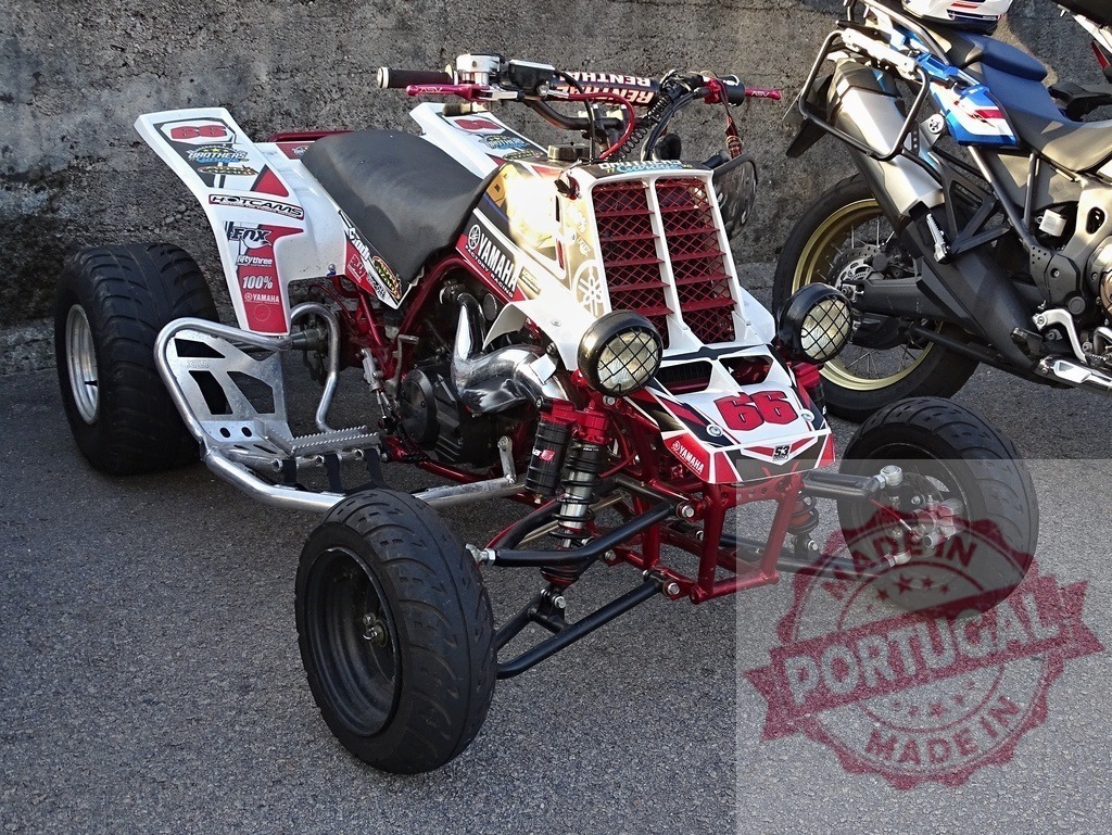Yamaha Banshee 350 customized quad for racing and fun | Customized Yamaha Banshee 350 quad parked near a wall, showing its modifications for racing and entertainment - Realized with Pictrs.com