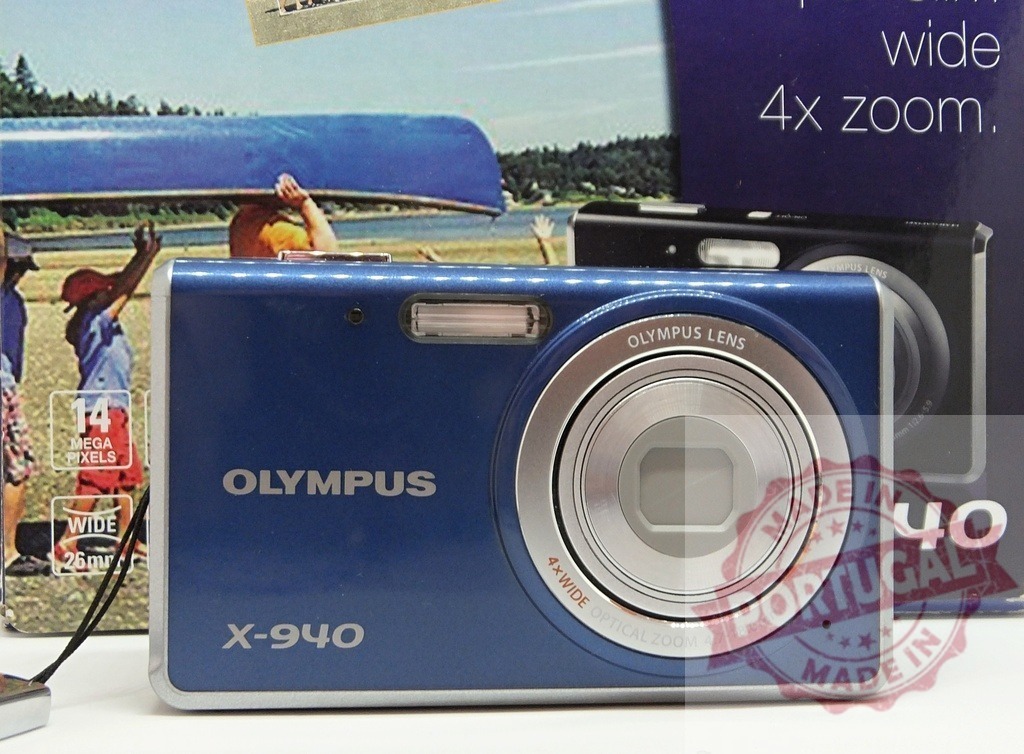 Olympus X-940 blue digital camera on display | Olympus X-940 blue compact point and shoot digital camera on a white background - Realized with Pictrs.com