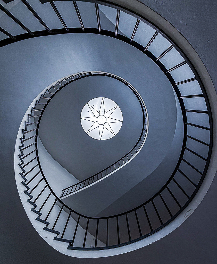 Endlose Symmetrie – Minimalistische Wendeltreppe | Eine faszinierende, perfekt zentrierte Perspektive einer modernen Wendeltreppe. Die schneckenförmige, endlose Geometrie und die kontrastreiche Lichtführung machen diese Architekturfotografie zu einem meisterhaften Kunstwerk des urbanen Minimalismus. Ein absoluter Design-Blickfang für moderne Wohnräume, Lofts oder Büros. Empfohlen als Großformat auf Acrylglas für maximale Tiefenwirkung. - Realisiert mit Pictrs.com