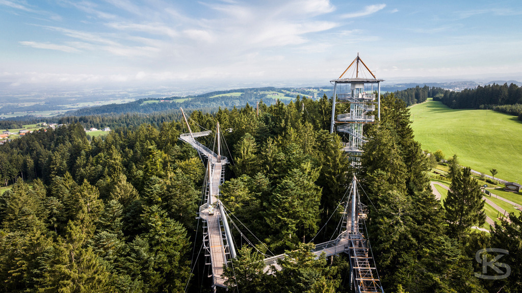 Baumwipfelpfad der Waldwelt Skywalk Allgäu aus der Vogelperspektive | Erleben Sie den Skywalk Allgäu in Scheidegg aus einer einzigartigen Perspektive. Diese beeindruckende Drohnenaufnahme zeigt die Architektur des 540 Meter langen, barrierefreien Baumwipfelpfads inmitten der dichten Wälder des Westallgäus. Ein ideales Motiv für Reiseberichte und Informationen über eines der beliebtesten Natur-Ausflugsziele Süddeutschlands mit Blick bis zu den Alpen und zum Bodensee - Realisiert mit Pictrs.com