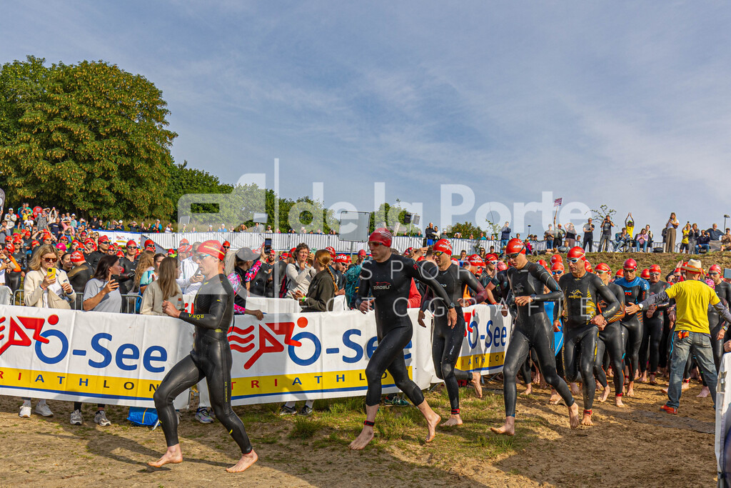 Rote Kappen wohin man auch blickt - über die Mitteldistanz gingen 300 Teilnehmer an den Start und sind hier auf dem Weg ins Wasser. | immodelaporte-sportfotos - Realisiert mit Pictrs.com