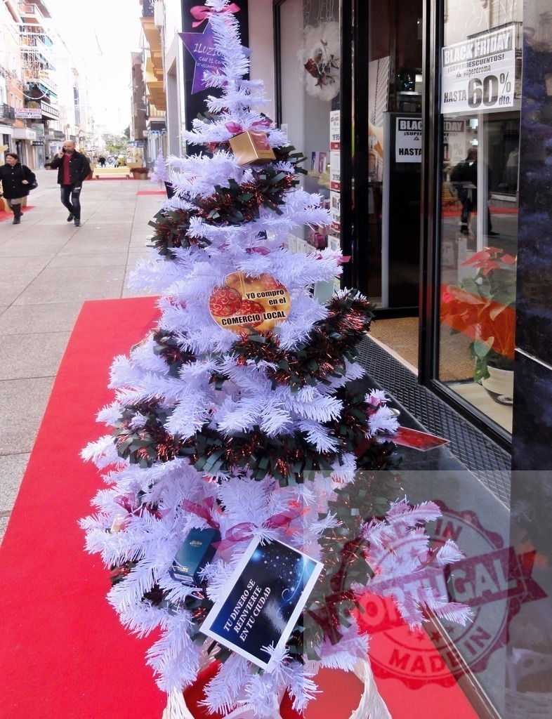 White christmas tree promoting local commerce during Black Friday sales | White christmas tree with gifts and signs promoting local shops during Black Friday sales - Realisiert mit Pictrs.com
