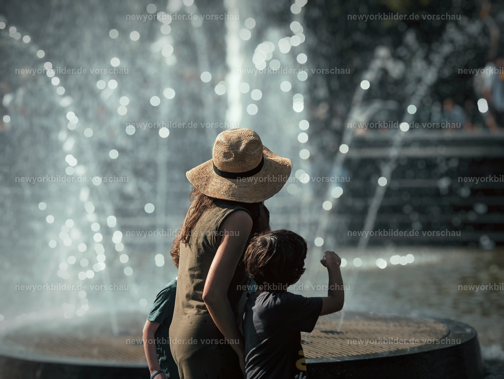 Sommerfreude im Washington Square Park – Familie genießt den Tag am Brunnen | Der Washington Square Park ist einer der lebendigsten Orte in Manhattan – ein Treffpunkt für Menschen, Musik und Momente voller Lebensfreude. Dieses Bild zeigt eine Mutter mit ihren beiden Kindern, die den Sommertag in vollen Zügen genießen. Der Springbrunnen sprüht erfrischende Tropfen, die in der Sonne glitzern, während die Kinder lachend immer wieder ins Wasser greifen. Die Szene ist voller Wärme und Leichtigkeit: das Lachen der Familie, die strahlende Sonne, die entspannte Atmosphäre des Parks. Hier verschmelzen urbane Energie und Natur zu einem Ort, an dem man den Alltag vergisst. Für mich sind solche Augenblicke die wahre Seele von New York – nicht nur Wolkenkratzer und Straßenlärm, sondern auch diese kleinen, glücklichen Szenen, die zeigen, wie Menschen die Stadt lieben und leben. Dieses Foto ist ein Symbol für Gemeinschaft, Freude und die Magie des Sommers in einer Metropole, die niemals stillsteht.