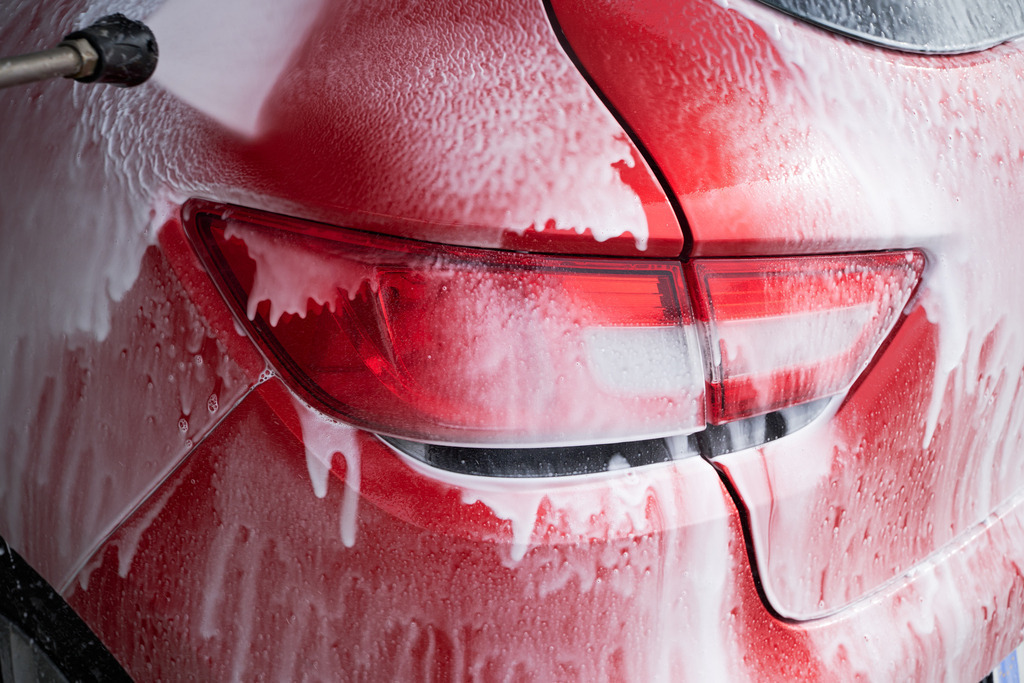 ein rotes Auto wird mit einer Waschlanze gewaschen | Wien, Austria - March 11, 2023: ein rotes Auto wird mit einer Waschlanze gewaschen. - Realisiert mit Pictrs.com