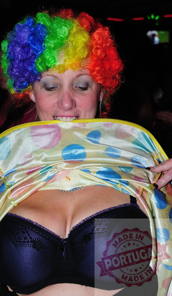 Playful woman wearing colorful clown wig lifting polka dot fabric revealing cleavage | Woman wearing colorful clown wig lifting polka dot fabric revealing cleavage at party - Realisiert mit Pictrs.com