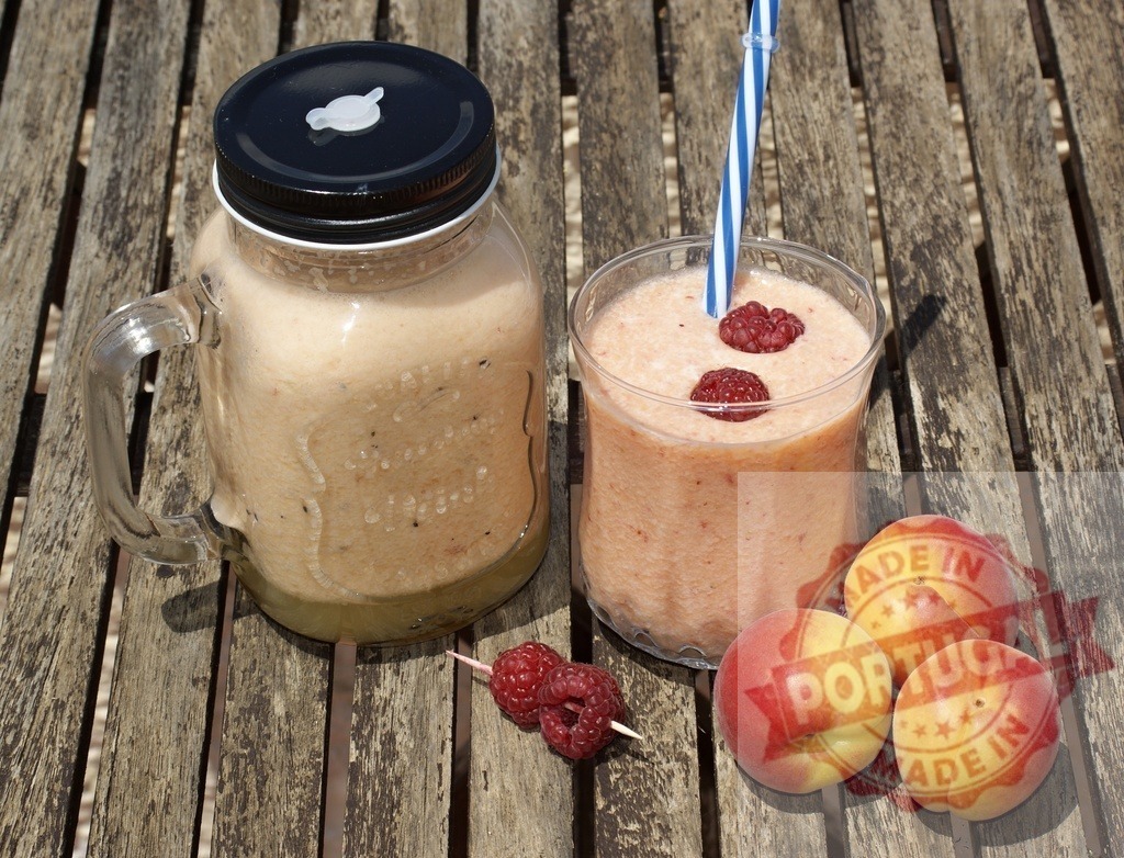 Peach and raspberry smoothie on rustic wood table | Fresh peach and raspberry smoothie in glasses, garnished with fruit on a wooden table - Realisiert mit Pictrs.com