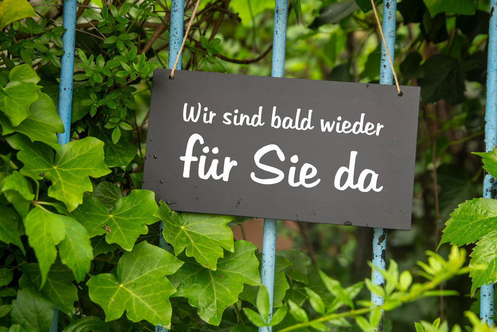 Symbolbild Betriebsferien: Schild am Garten mit der Aufschrift WIR SIND BALD WIEDER FÜR SIE DA | Symbolbild Betriebsferien: Schild am Garten mit der Aufschrift WIR SIND BALD WIEDER FÜR SIE DA - Realisiert mit Pictrs.com