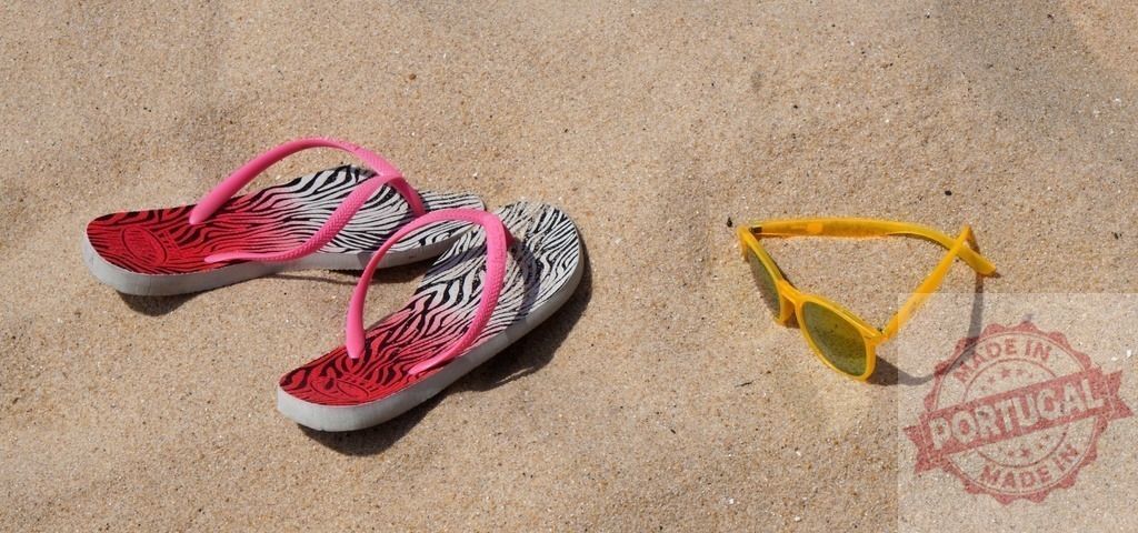 Flip-flops and sunglasses relaxing on sandy beach | Pink zebra print flip-flops and trendy yellow sunglasses resting on warm beach sand - Realized with Pictrs.com