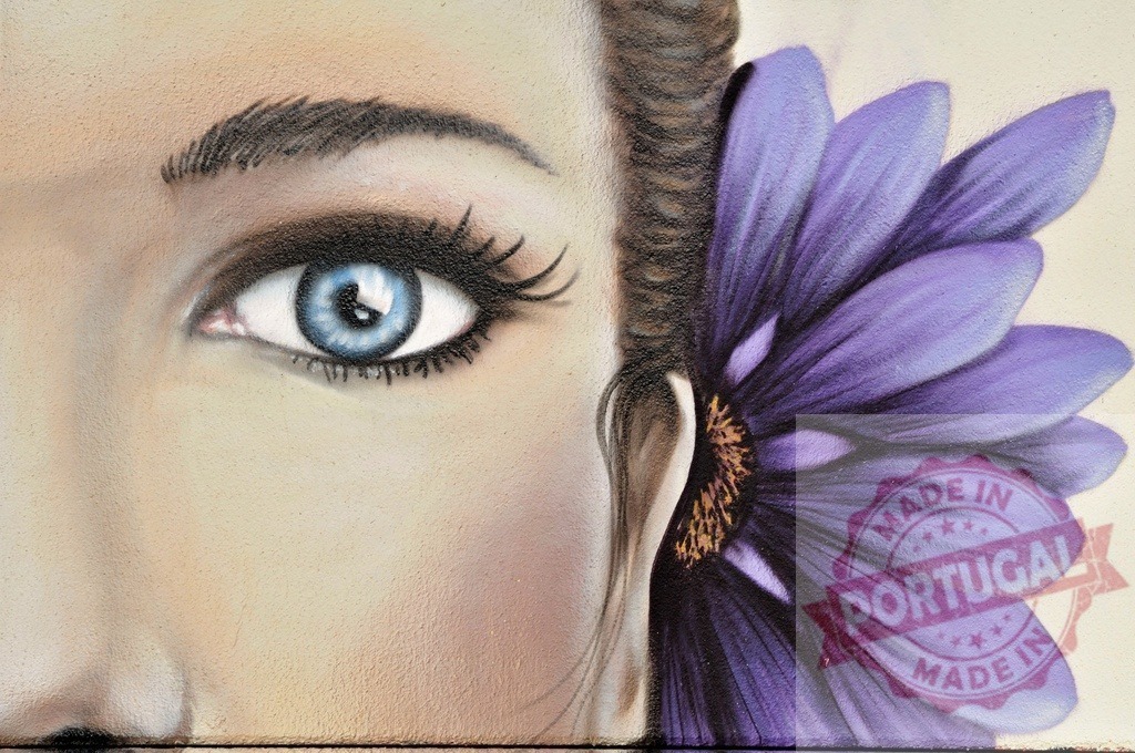 Woman with blue eye and purple flower painted on a wall | Urban art representing part of a female face with a purple flower painted near the ear - Realized with Pictrs.com