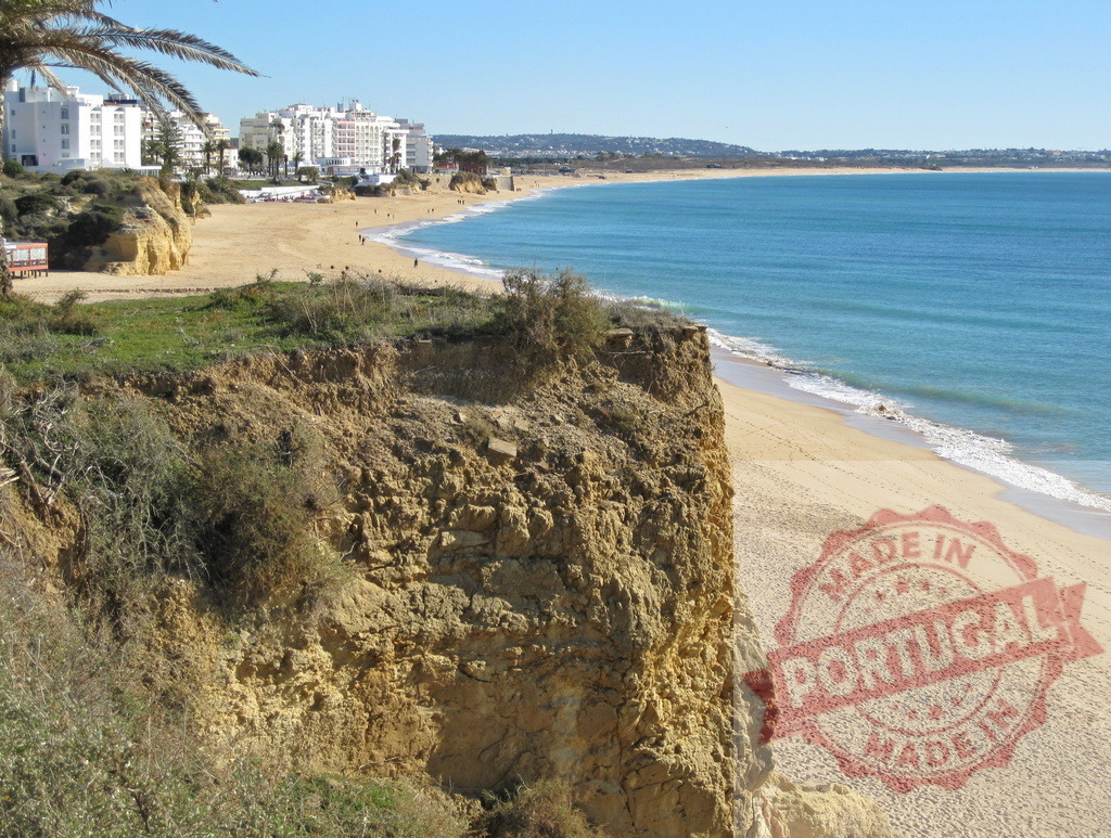 Armação de Pêra beach coastline and resort buildings. Algarve - Silves | Armação de Pêra coastline featuring cliffs, sandy beach, Atlantic Ocean, and resort buildings - Realisiert mit Pictrs.com