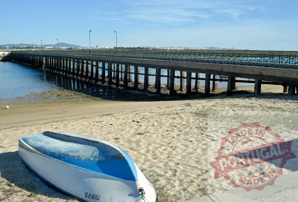 Abandoned boat on beach by pier | Boat abandoned on sandy beach with a long pier extending over the water - Realisiert mit Pictrs.com