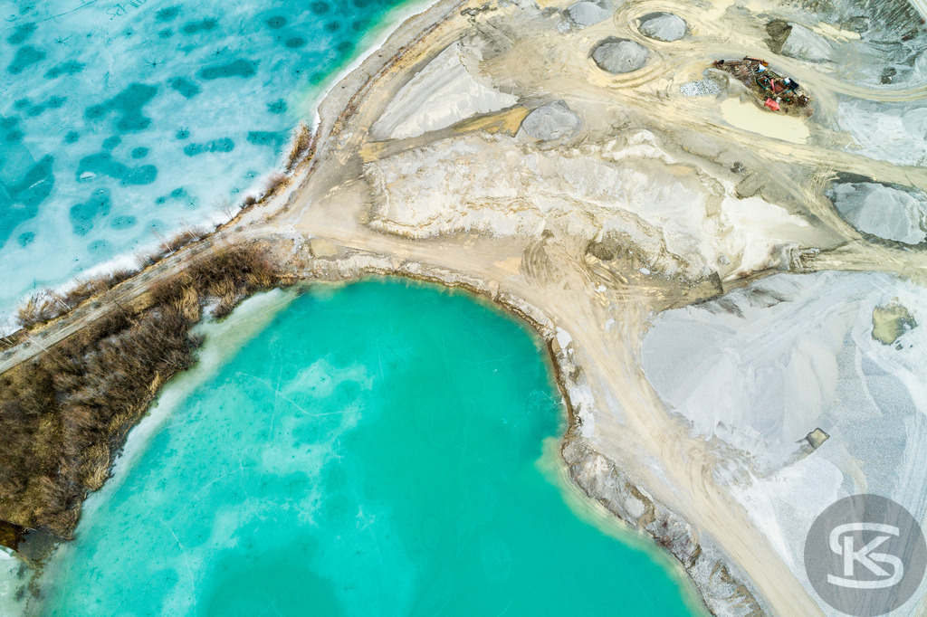Zugefrorene Kiesgrube aus der Luft – Faszinierende Winterlandschaft als Drohnenaufnahme | Beeindruckende Luftaufnahme einer zugefrorenen Kiesgrube im Winter. Die Drohnenfotografie zeigt türkisblaues Eis und abstrakte Naturmuster aus der Vogelperspektive – einzigartige Winterlandschaft von oben. - Realisiert mit Pictrs.com