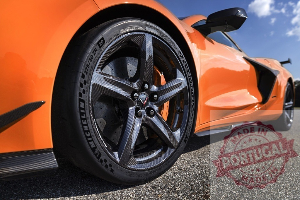 Orange Chevrolet Corvette Z06 carbon fiber wheel detail | Chevrolet Corvette Z06 with carbon fiber wheel on pavement under blue sky - Realized with Pictrs.com