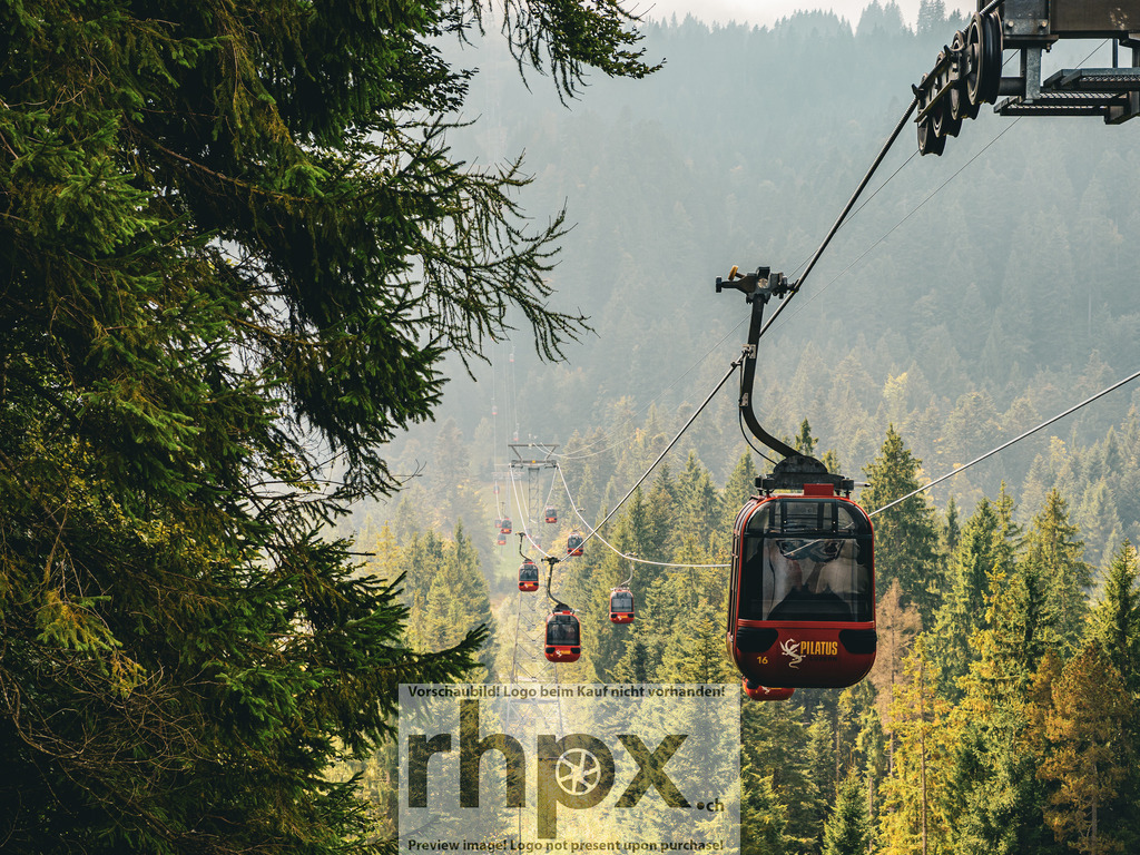Pilatus Gondelfahrt | <p><strong>Weite. Wald. Schweben.</strong></p><p>Die rote Panoramagondel gleitet erhaben über die dichten, grünen Nadelwälder am Pilatus. Inmitten der Natur geniesst du das Gefühl der Schwerelosigkeit und den Blick auf die vorbeiziehende Bergwelt.</p><p>Wähle unter "Produktauswahl" dein Wunschformat: Vom klassischen Wandbild über Puzzle & Tassen bis zum digitalen Download (z.B. als Handy-Hintergrund).</p> - Realisiert mit Pictrs.com