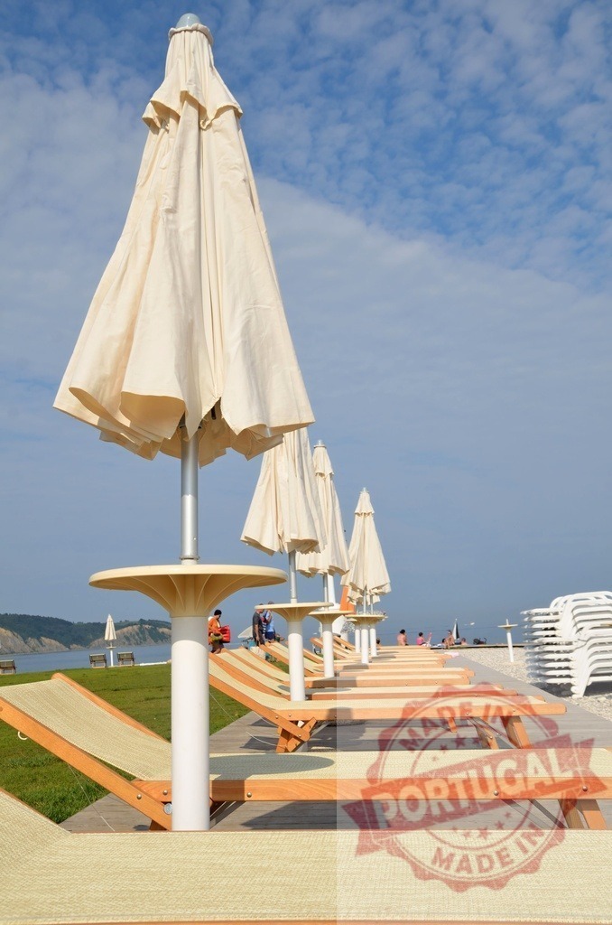 Beach umbrellas and sun loungers on a resort beach | Closed umbrellas and empty sun loungers arranged on a resort beach, preparing for relaxation - Realized with Pictrs.com