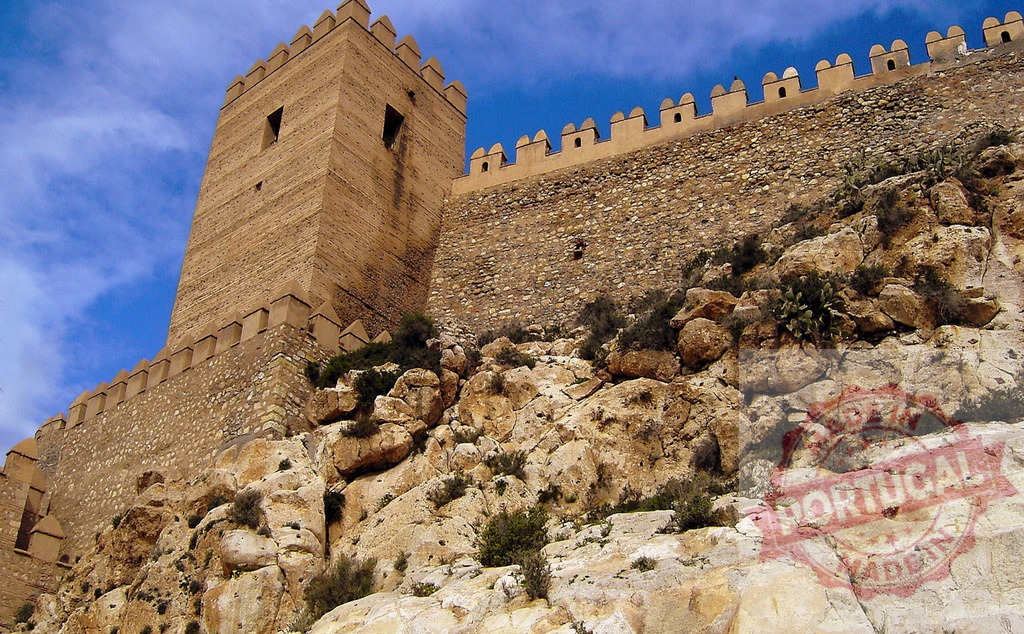 Alcazaba fortress wall and tower in Almería, Spain | Alcazaba defensive walls and tower built on a rocky hill under a blue sky - Realized with Pictrs.com