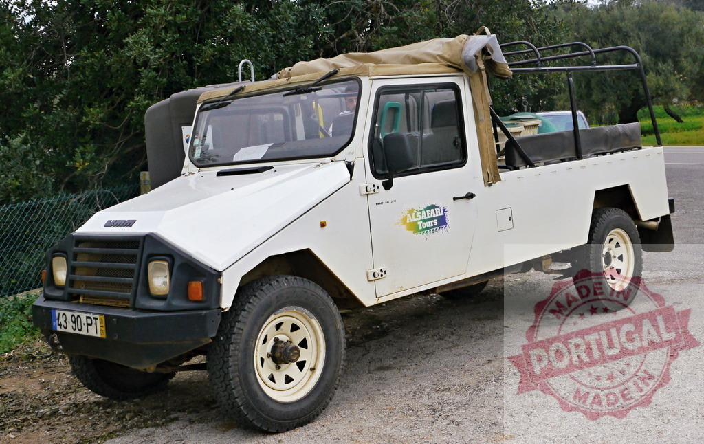 White UMM Alter safari vehicle for adventure tours | UMM Alter 4x4 pickup truck parked on a gravel road, used for safari tours - Realized with Pictrs.com