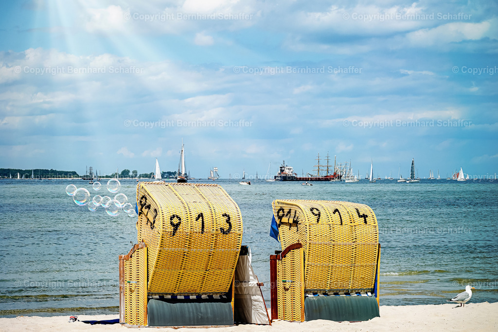 Strandszene typisch | Zwei Strandkörbe an einem Sandstrand der Ostsee mit Seifenblasen und vielen Schiffen auf dem Meer am Horizont.  - Realisiert mit Pictrs.com