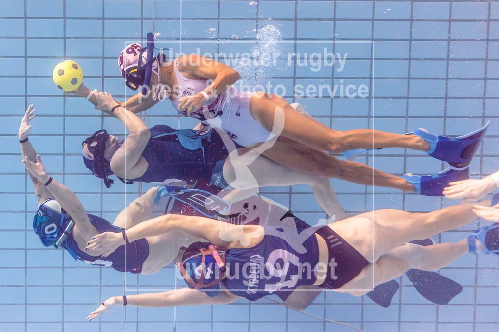 24. - 26.11.2023: Unterwasser-Rugby Champions Cup 2023  | Damen-Spiel um Platz 5:  Amager Uv-Rugby (Dänemark) in blau gegen UWRC Wien / Österreich in weiß. Bilim Erbas (weiß #95) bringt den Spielball in die gegnerische Hälft und wird dabei direkt von drei dänischen Gegenspielerinnen angegriffen. - Realisiert mit Pictrs.com
