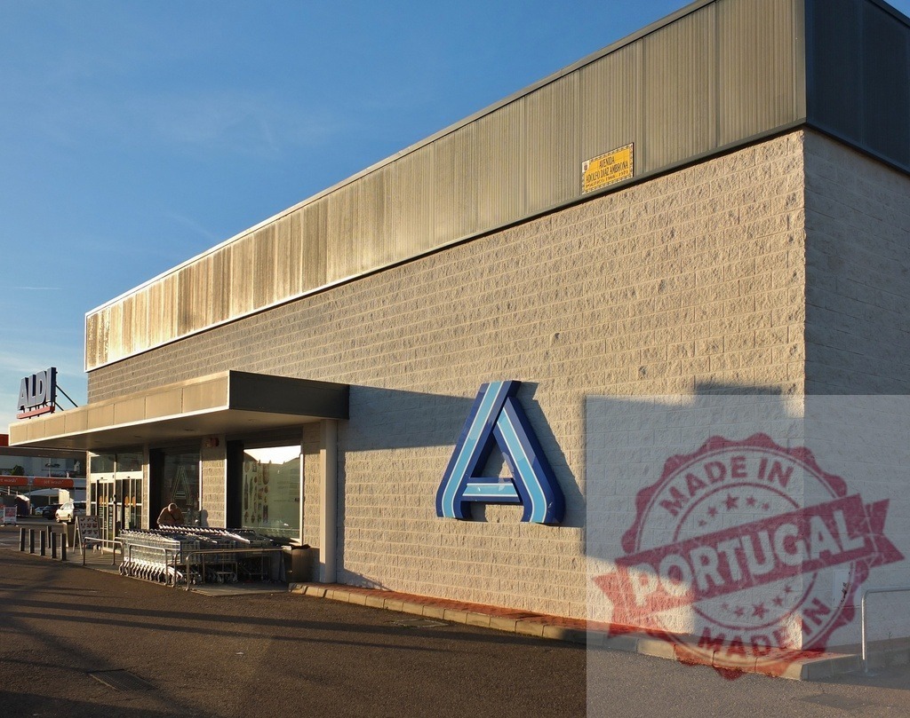 Aldi supermarket exterior with logo and shopping carts | Aldi supermarket building facade in sunlight with logo, entrance, and shopping carts - Realisiert mit Pictrs.com