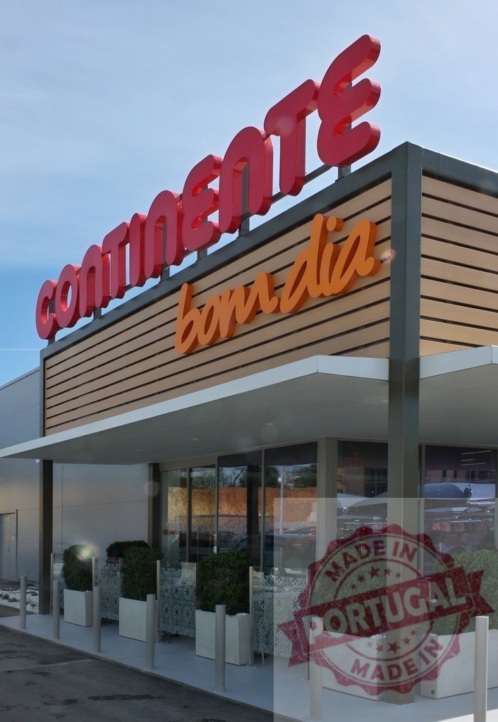 Continente Bom Dia supermarket exterior in Portugal with sign | Continente Bom Dia supermarket storefront with its distinctive red and orange signage against a blue sky - Realisiert mit Pictrs.com