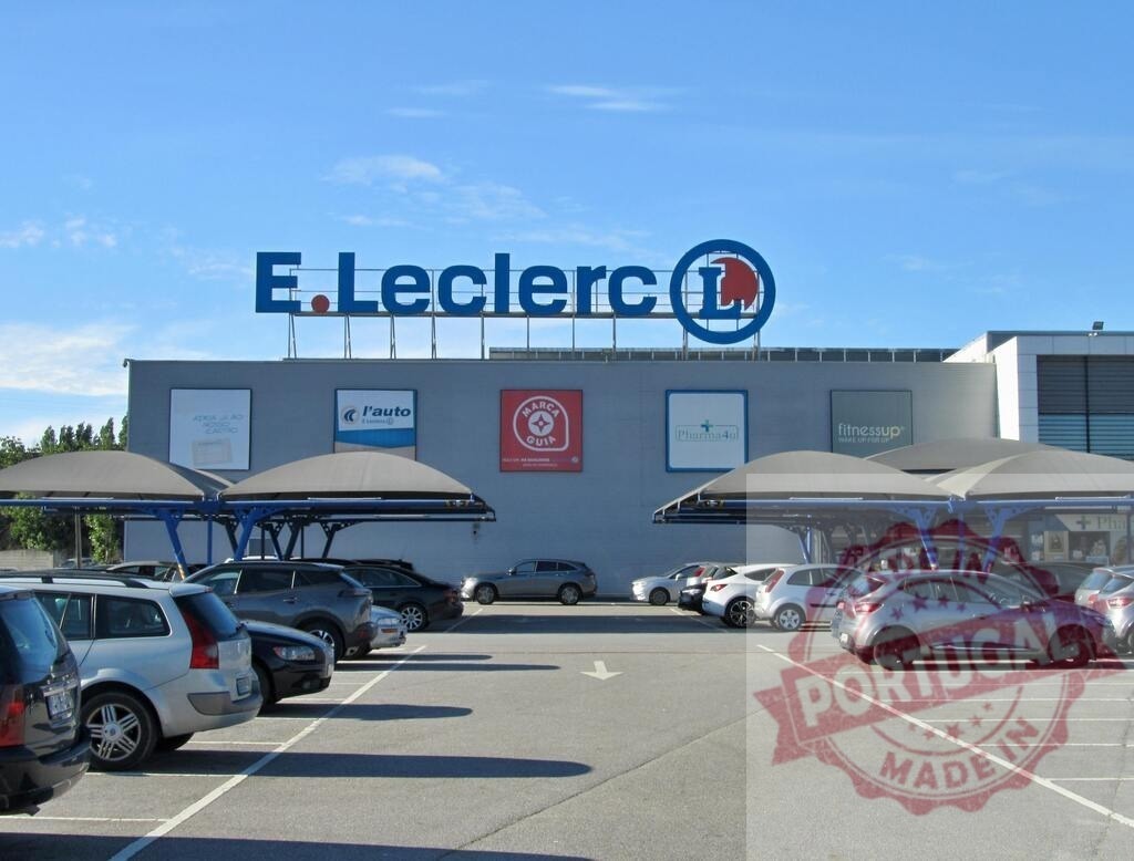 E.Leclerc hypermarket building with parked cars | E.Leclerc hypermarket with its large parking lot filling with cars on a sunny day - Realized with Pictrs.com