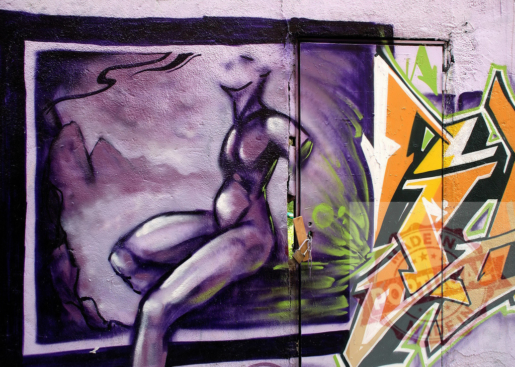 Purple female figure relaxing in a graffiti painting with orange and yellow tags | Graffiti art representing a purple female figure sitting on a ledge with orange and yellow tags on the right - Realized with Pictrs.com