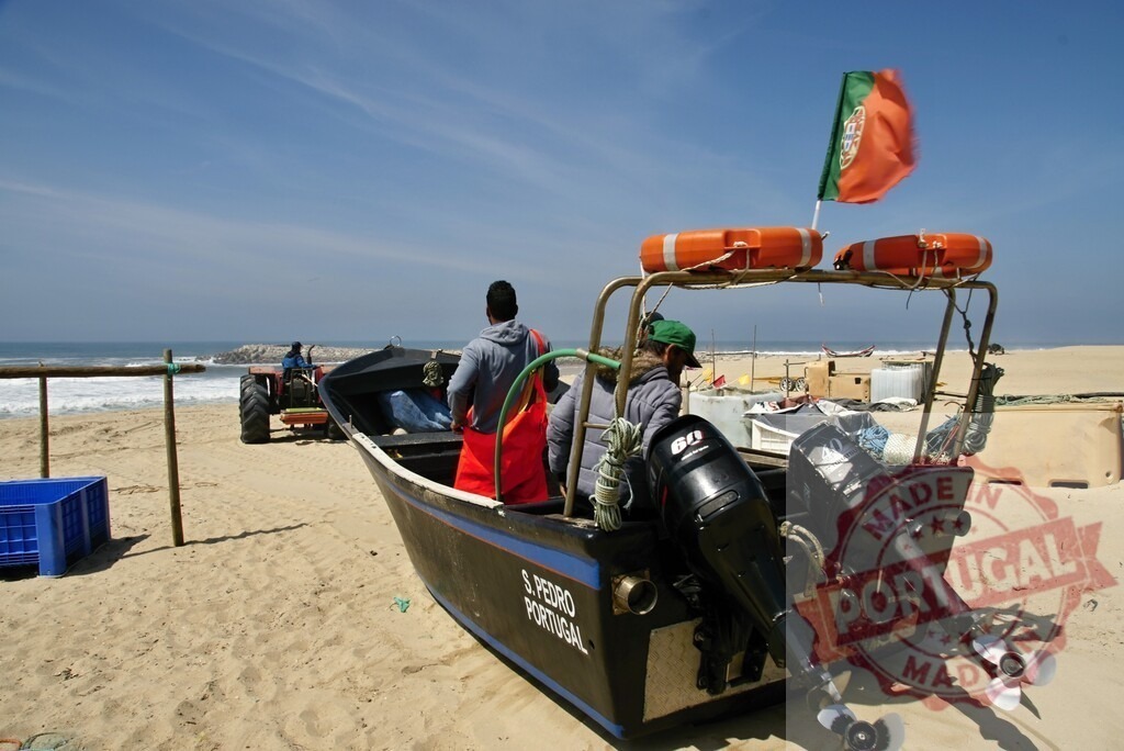 Portuguese fishermen preparing fishing boat on sandy beach | Fishermen preparing their boat with a Portuguese flag before going out to sea on a sunny day - Realized with Pictrs.com