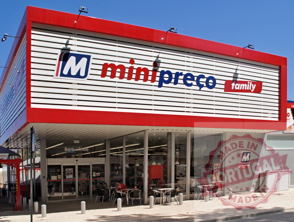 Minipreço Family supermarket exterior on a sunny day | Minipreço Family supermarket building with a red and white facade, entrance, and outdoor cafe area - Realisiert mit Pictrs.com