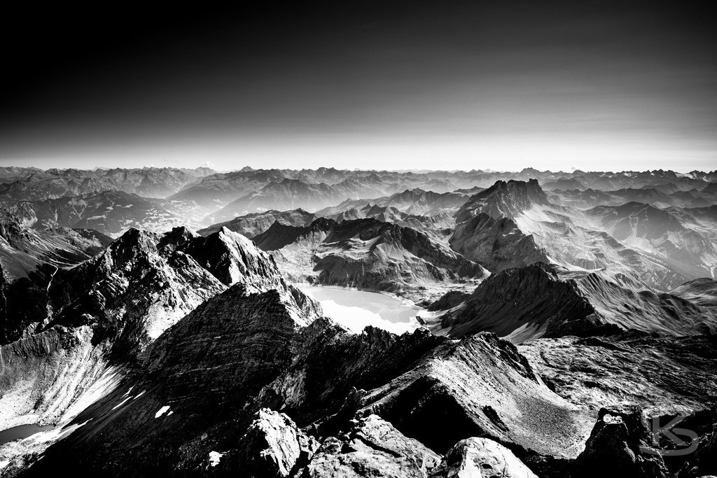 Blick vom Gipfel der Schesaplana - Rätikon Gebirgsmassiv Vorarlberg, Graubünden | Majestätischer Blick von der Schesaplana im Rätikon, Monumentales Schwarzweiß-Foto mit dramatischem Himmel. Der höchste Gipfel des Rätikon-Massivs erhebt sich über schroffe Geröllhänge und beeindruckt mit seiner markanten Felsformation an der Grenze zwischen Vorarlberg und Graubünden. - Realisiert mit Pictrs.com