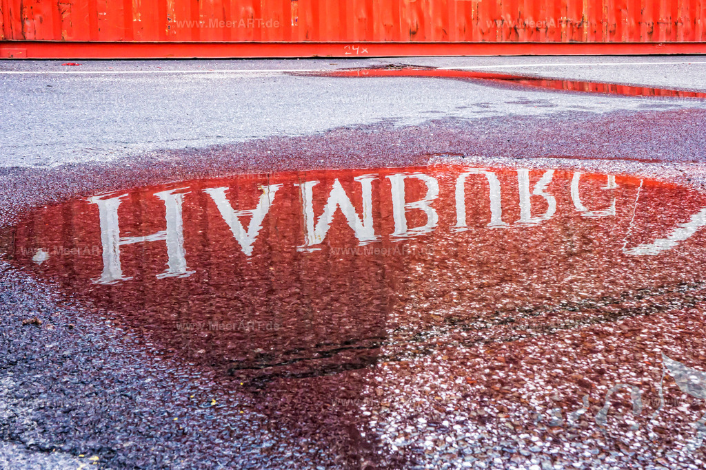 Hamburger Hafen | Die Aufschrift von einem Container spiegelt sich in einer Pfütze |The inscription of a container is reflected in a puddle| - Realisiert mit Pictrs.com