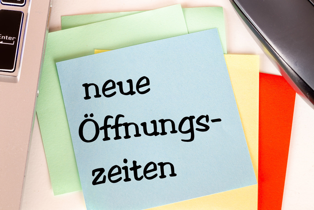 NEUE ÖFFNUNGSZEITEN ; Zettel auf einem Schreibtisch | Notizzettel mit der Aufschrift NEUE ÖFFNUNGSZEITEN auf einem Schreibtisch - Realisiert mit Pictrs.com