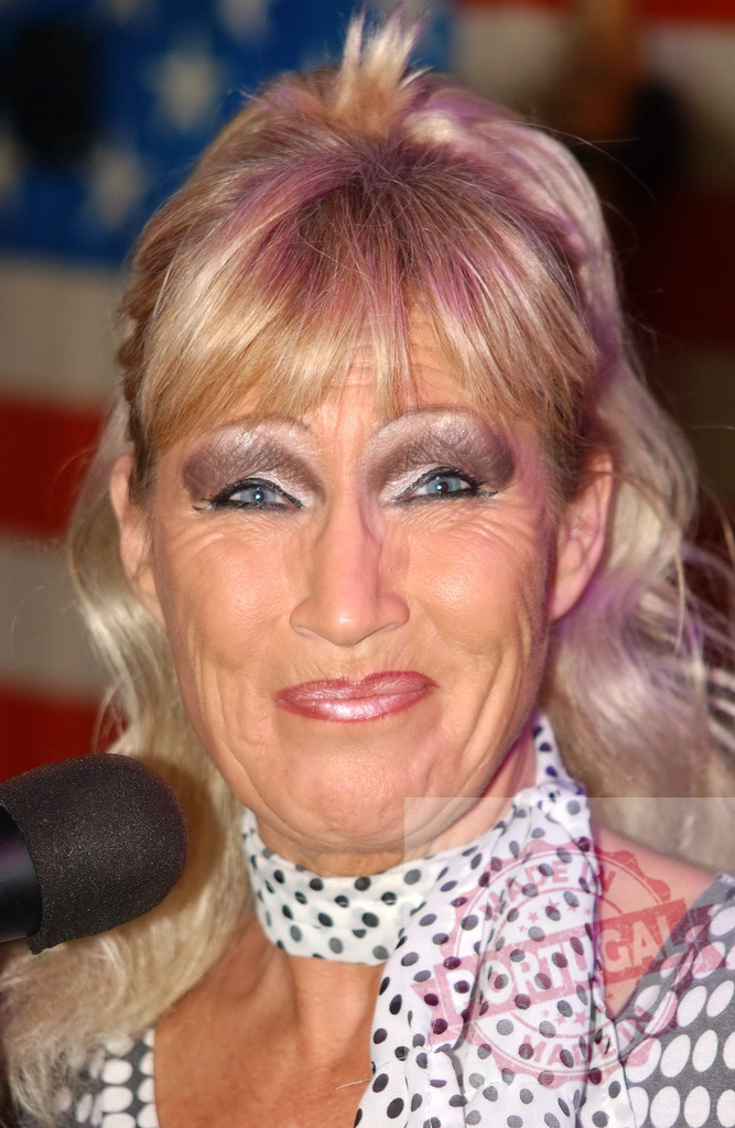 Gitte Hænning performing with microphone celebrating American spirit | Gitte Hænning singing, wearing a polka dot scarf in front of an American flag - Realisiert mit Pictrs.com