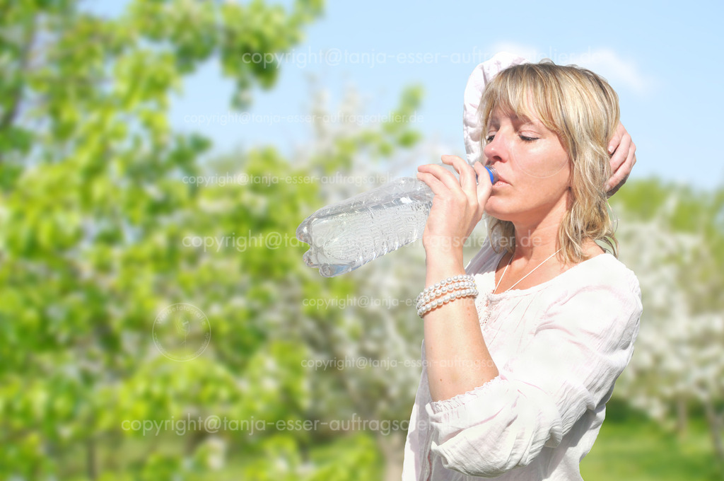 Blond woman drinks water from a bottle of PET | Eine blonde Frau in weißer Bluse steht in blühender Landschaft und trinkt Wasser aus einer PET Flasche. Natürlicher Durstlöscher. 