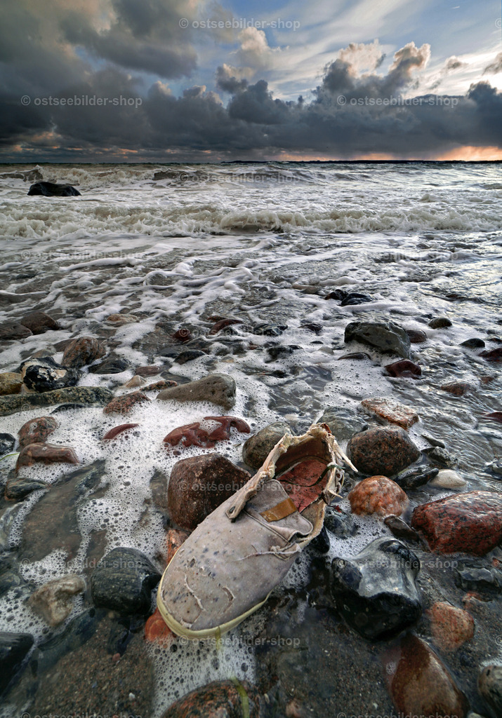 Turnschuh auf Seereise | Ein einzelner Turnschuh wird durch Wellen nach langer Reise über das Meer an Land getragen.