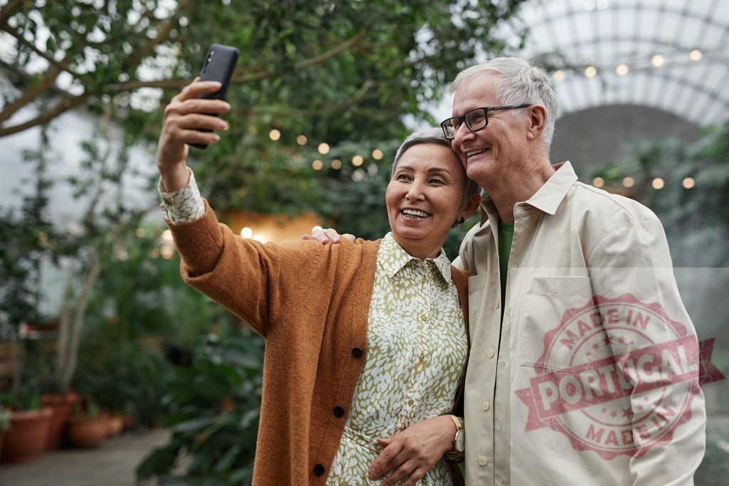 Happy senior couple taking selfie in greenhouse | Senior couple smiling and taking a selfie with smartphone in a greenhouse - Realized with Pictrs.com