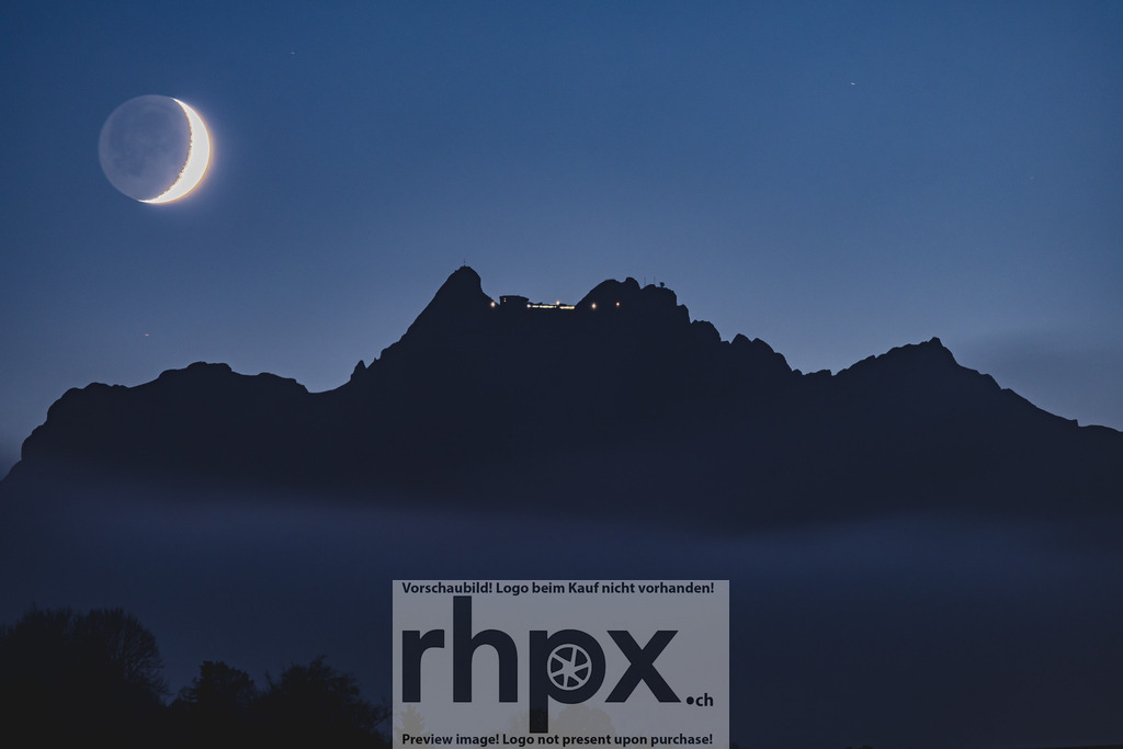 Mondaufgang über dem Pilatus | Sichel. Fels. Mystik.Die leuchtende Mondsichel inszeniert sich perfekt hinter der markanten Silhouette des Pilatus-Kulm. Ein kraftvolles Bild voller Ruhe, das die nächtliche Magie und die erhabene Atmosphäre des Luzerner Hausbergs spürbar macht.Wähle unter "Produktauswahl" dein Wunschformat: Vom klassischen Wandbild über Puzzle &amp; Tassen bis zum digitalen Download (z.B. als Handy-Hintergrund). - Realisiert mit Pictrs.com