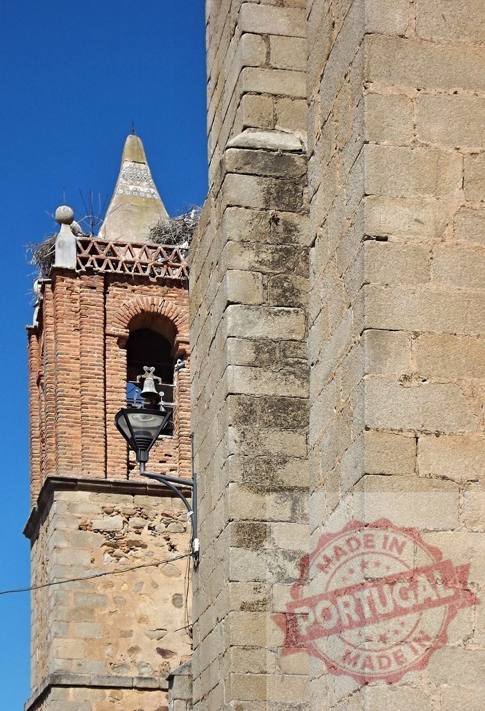 Ancient brick bell tower with stork nest. Spain - Extremadura | Stone church wall next to a brick bell tower against blue sky - Realisiert mit Pictrs.com