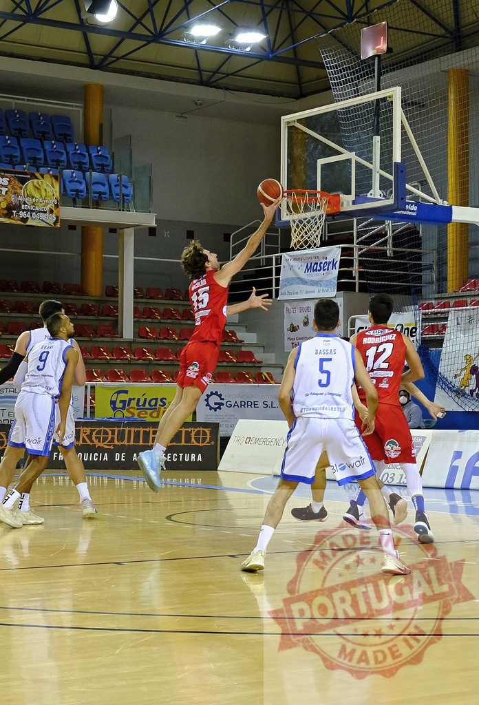 Basketball player jumping for a layup during game | Player in red jersey jumping high for a layup shot during an indoor basketball game - Realisiert mit Pictrs.com