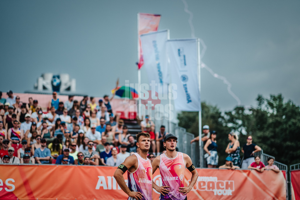 Beachvolleyball | Männer | German Beach Tour 2024 | Tourstop München | 20.07.2024 | v.l. Daniel Kirchner und Paul Henning, im Hintergrund ist ein Blitz zu sehen, ein Gewitter zieht auf